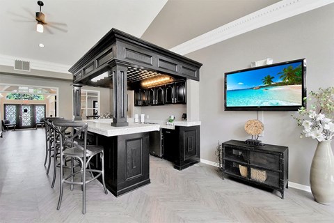 A modern kitchen with a bar area and a television displaying a beach scene.