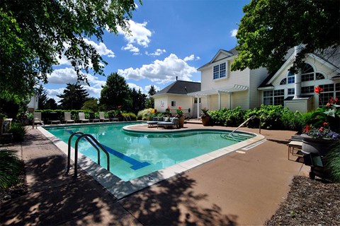 A pool surrounded by a house and trees.