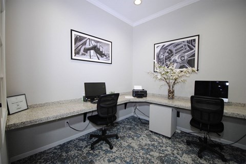A room with two desks and chairs, one of which has a laptop on it.