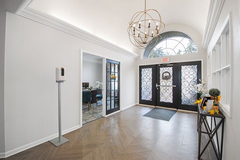 A hallway with a black door and a chandelier.