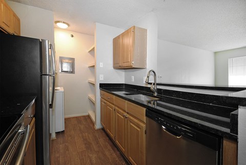 A kitchen with black countertops and wooden cabinets.