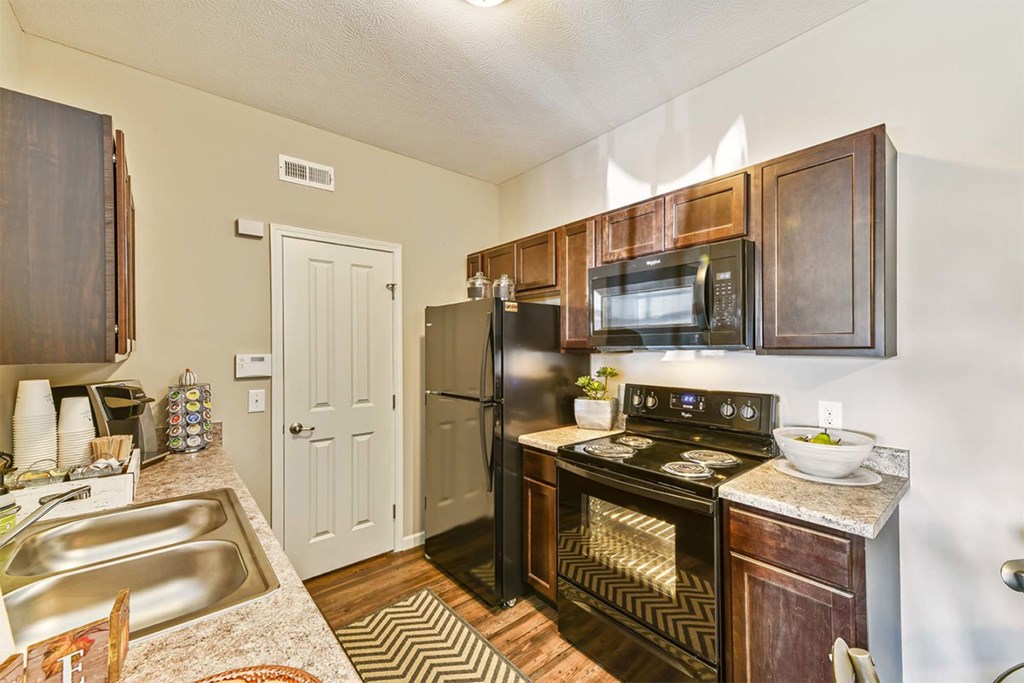 A kitchen with a sink, stove, and refrigerator.