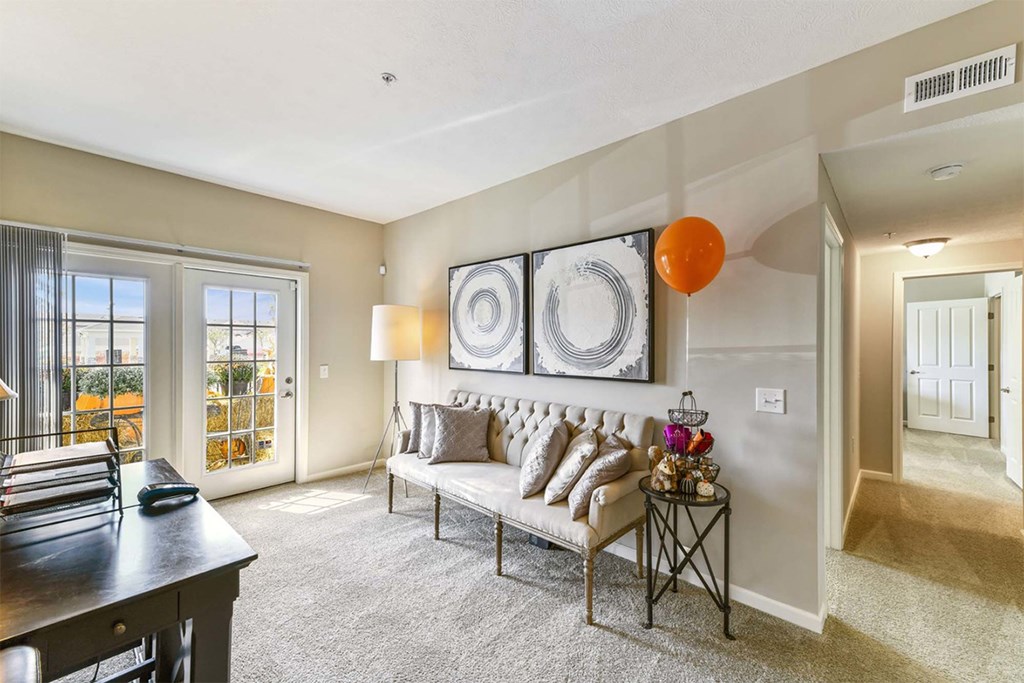 A living room with a couch, a table, and a painting on the wall.