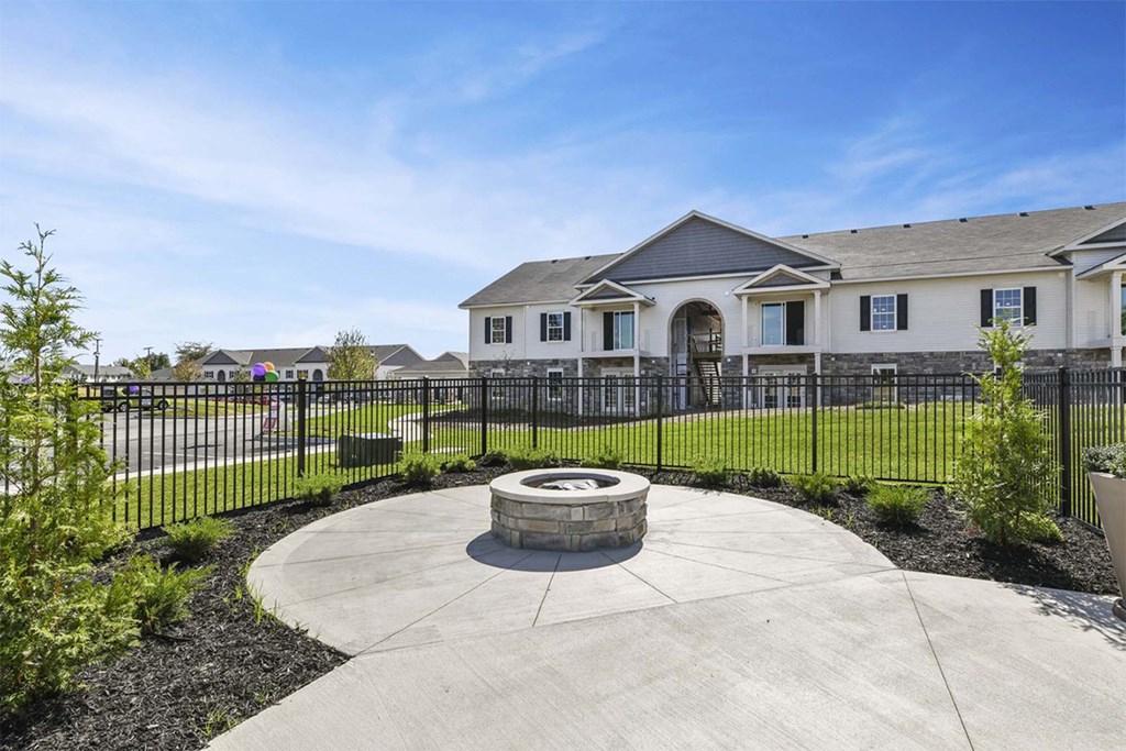 A residential area with a circular concrete walkway and a black fence.