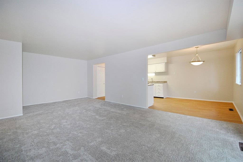 the living room and kitchen of an empty home with white walls