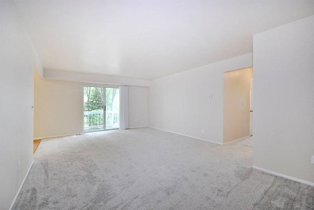 an empty living room with white walls and carpet