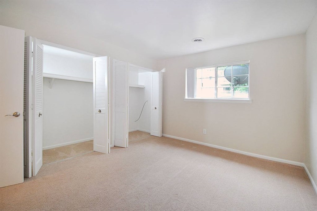 an empty bedroom with a closet and a window