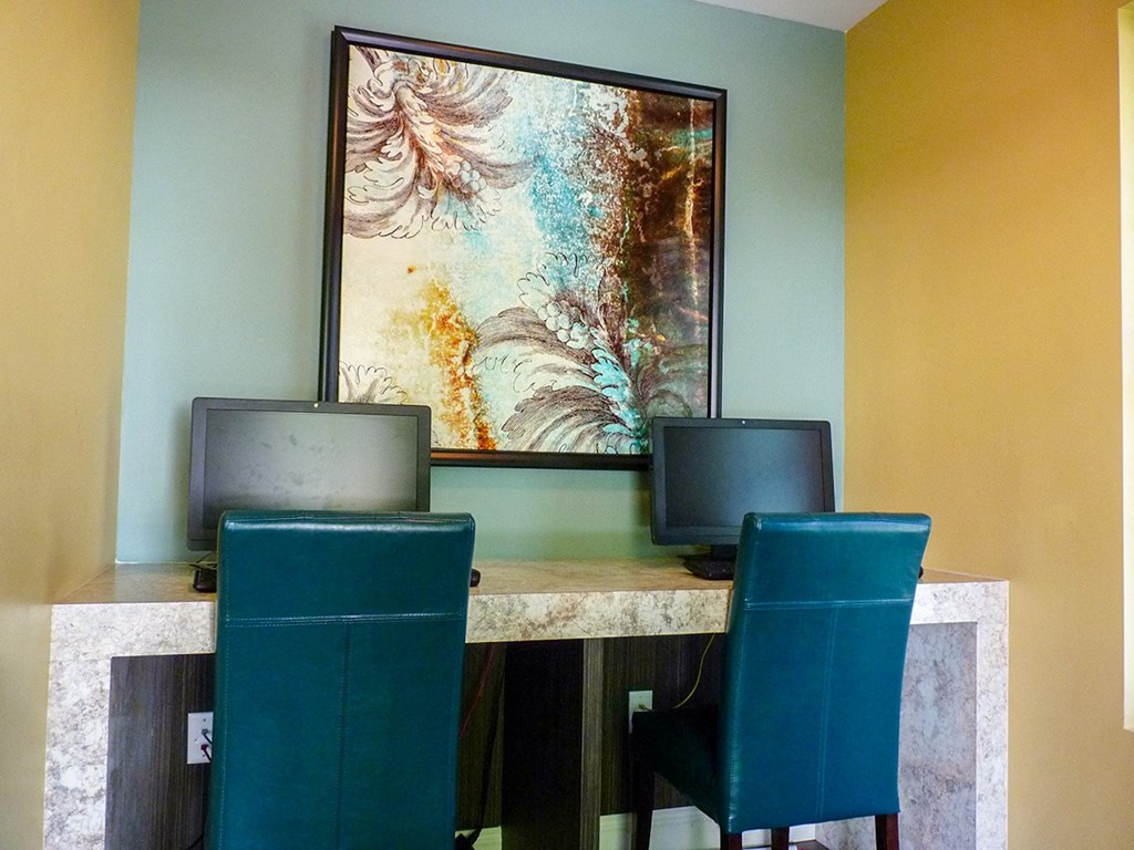 a desk with three chairs and a painting on the wall