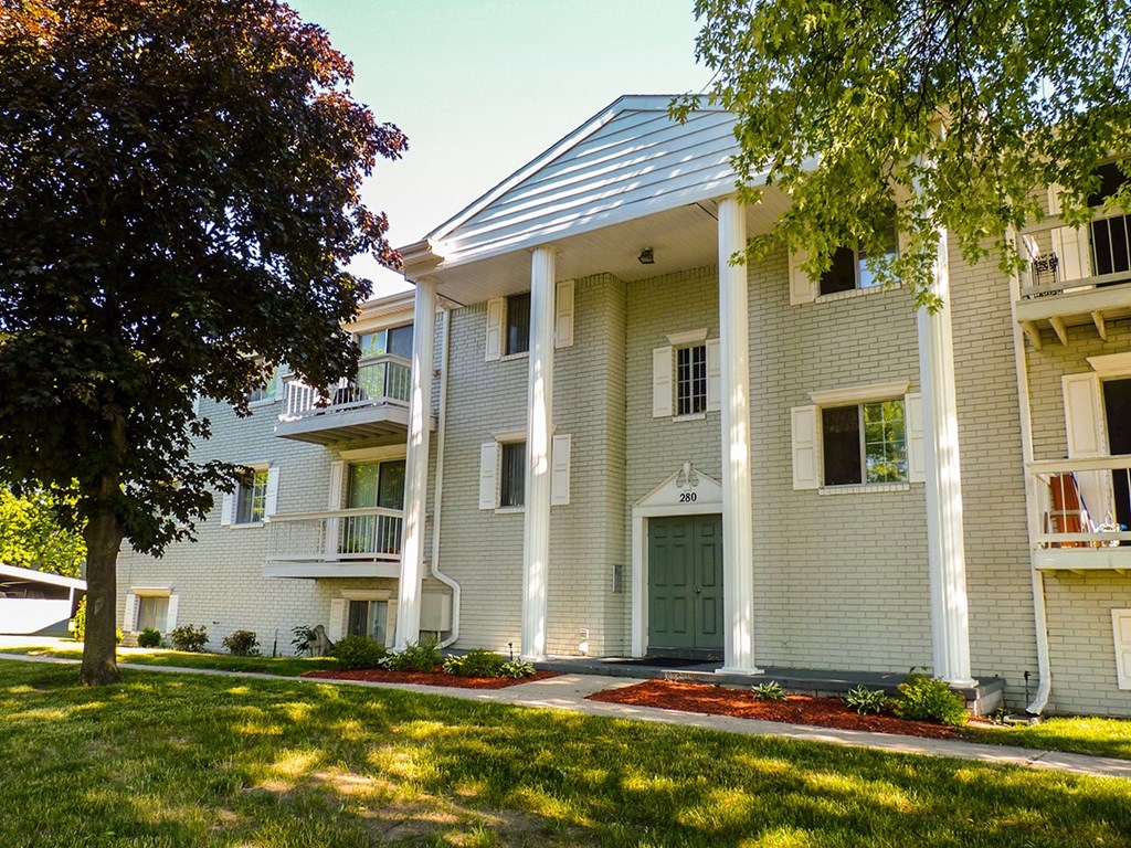 a white house with a green door and a tree
