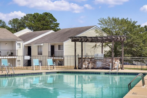 A swimming pool with a slide and chairs in front of a house.