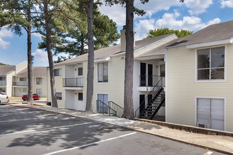 A row of apartment buildings with trees in front.