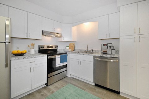 a white kitchen with stainless steel appliances and white cabinets