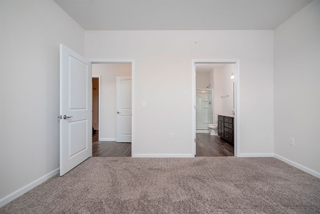 a bedroom with a carpeted floor and a door to a bathroom