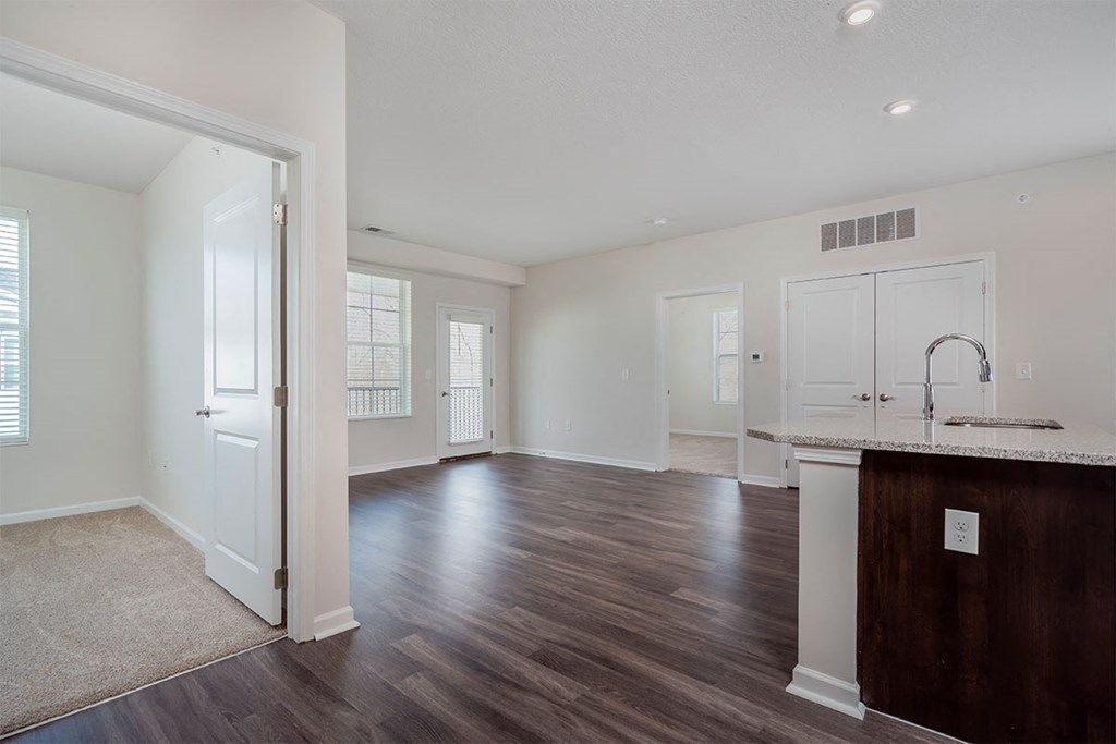 an empty living room and kitchen with hard wood flooring