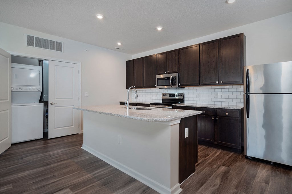 a kitchen with a large island and a stainless steel refrigerator