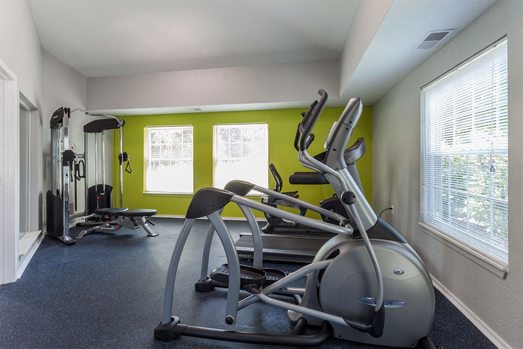 a gym with machines and weights in a room with green walls