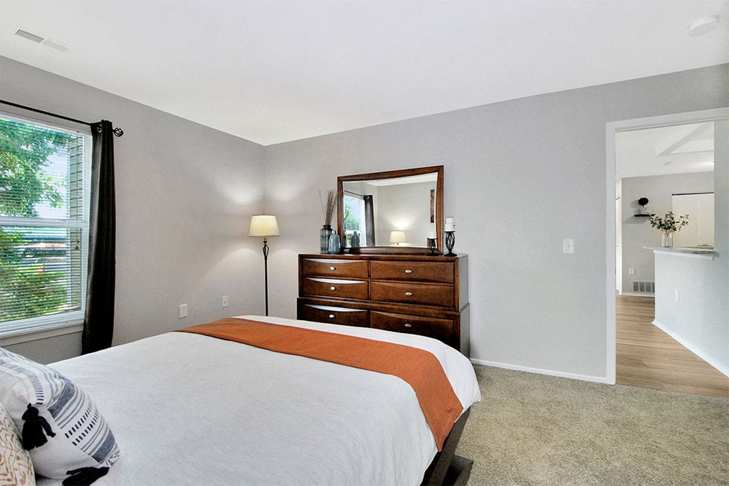 a bedroom with a bed and a dresser with a mirror