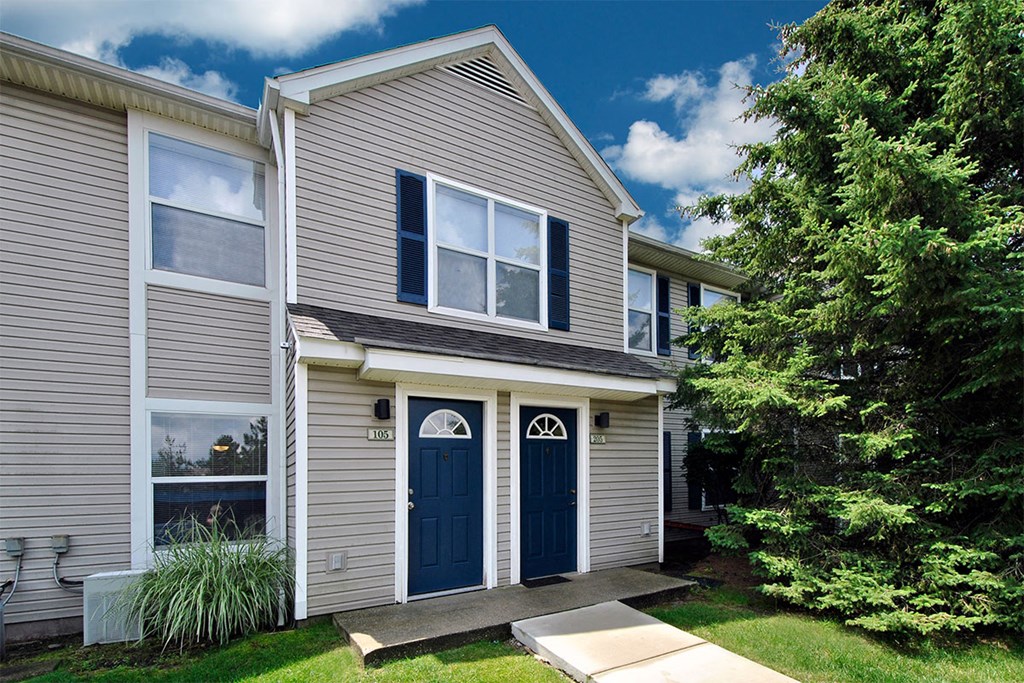 the front of a gray house with blue doors and a lawn