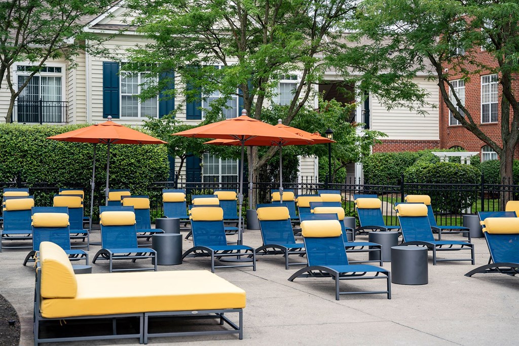 an outdoor lounge area with yellow and blue chairs and orange umbrellas
