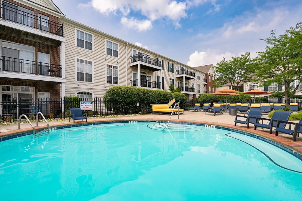 a swimming pool with lounge chairs and umbrellas in front of a building