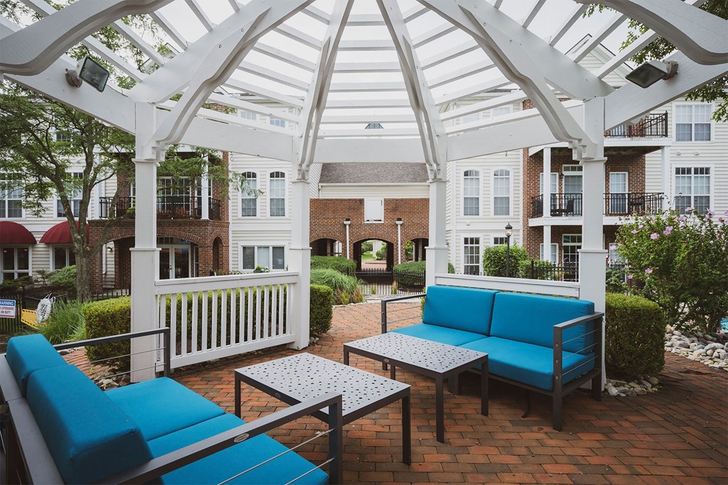 a patio with blue couches and tables in front of an apartment building