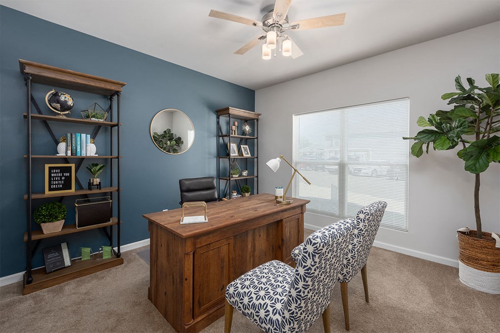 an office with blue walls and a large window and a desk with chairs