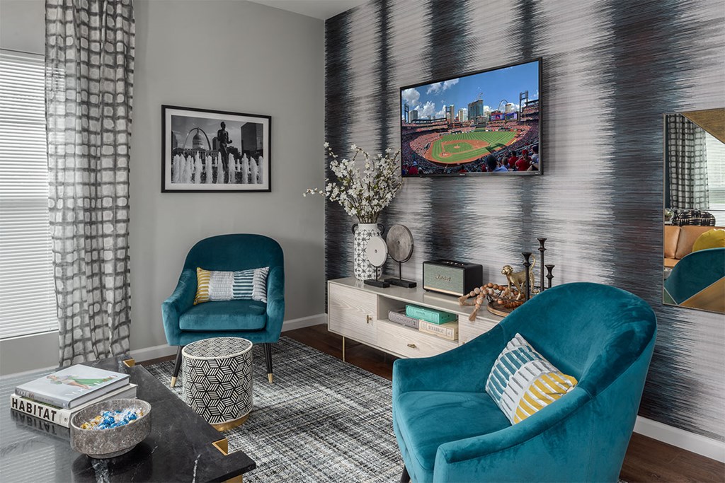 a living room with blue chairs and a tv on the wall