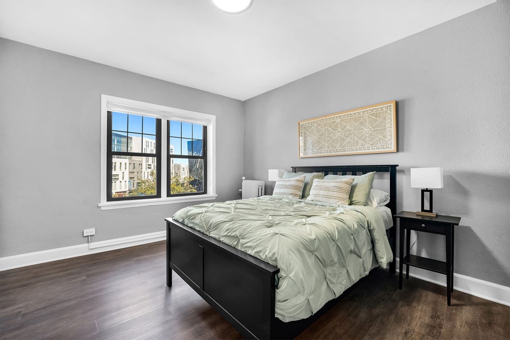 A bedroom with a large bed and a window overlooking a cityscape.