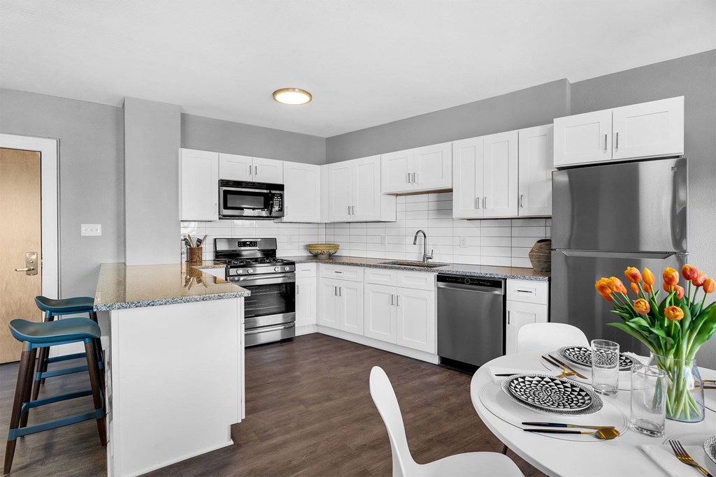 A modern kitchen with a dining table set for two.