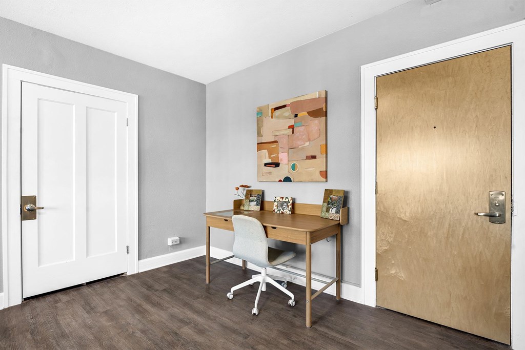 A room with a desk and a chair in front of a wooden door.
