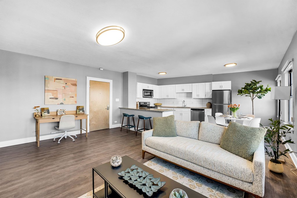 A modern living room with a couch, coffee table, and a kitchen in the background.