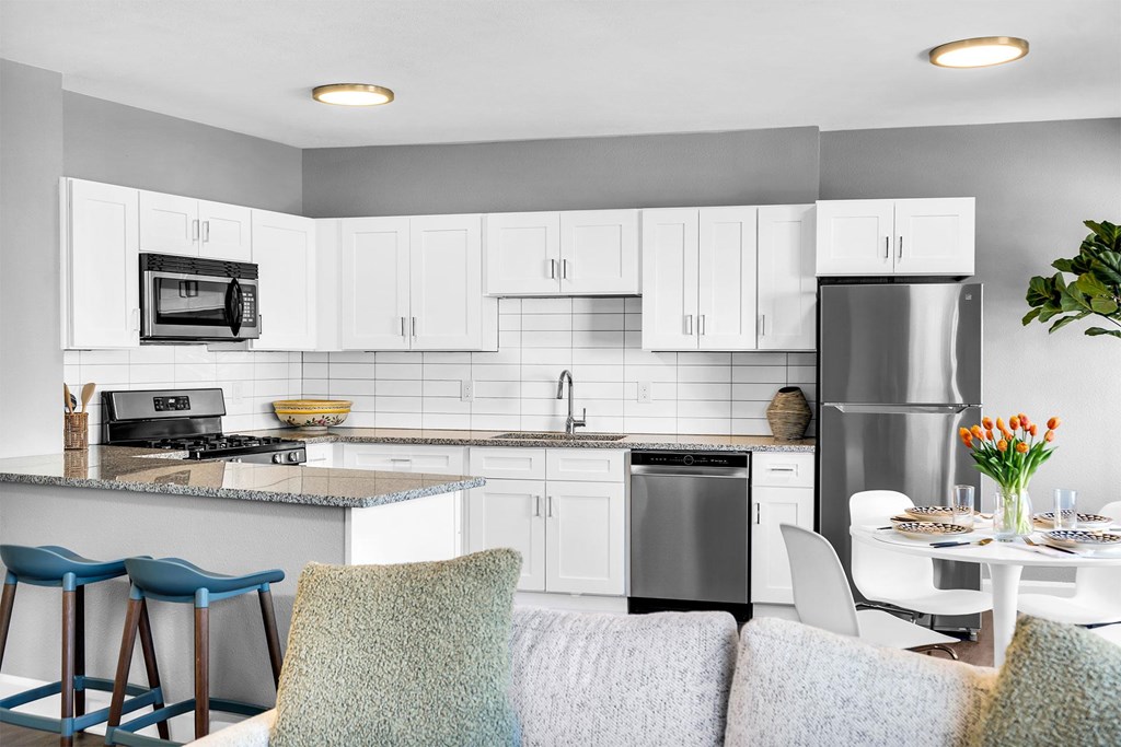 A modern kitchen with a dining table set for two.