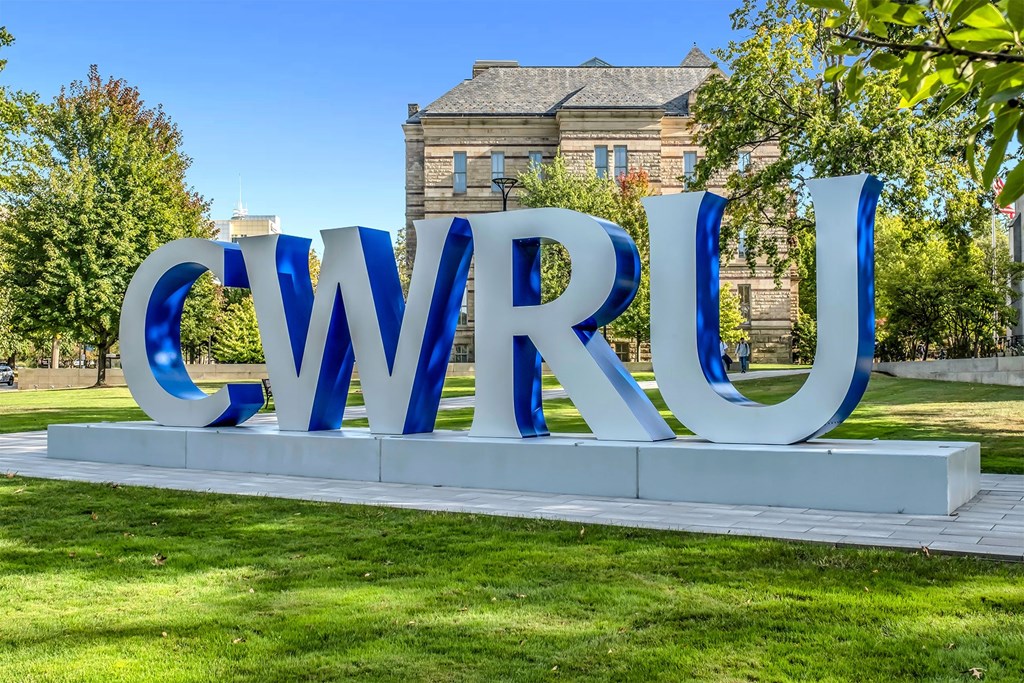 A large blue and white sign spelling out "CWRU" sits in front of a building.