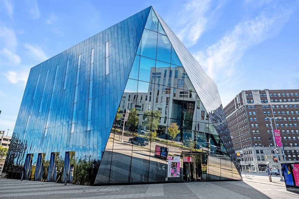 A modern building with a blue glass facade and a triangular shape.