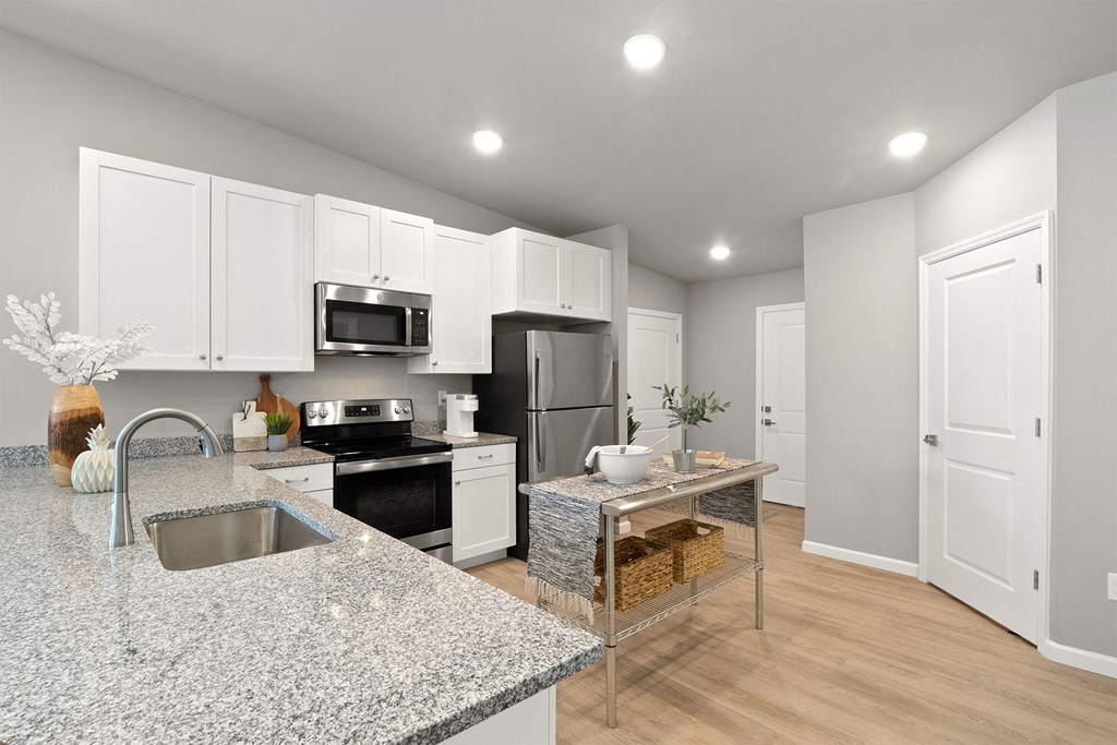 a renovated kitchen with granite counter tops and white cabinets
