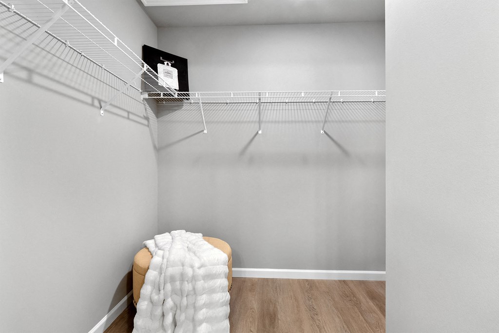 an empty closet with a chair and a wire rack on the wall