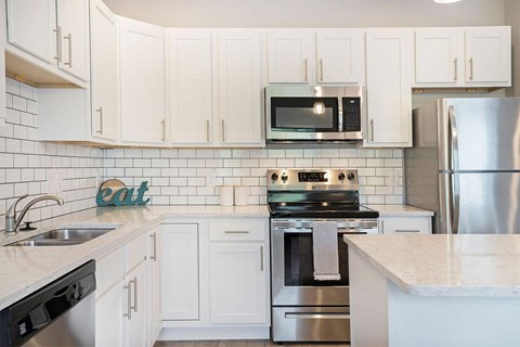 A kitchen with white cabinets and a stainless steel refrigerator.