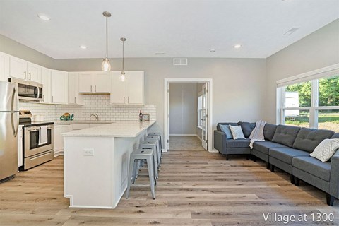 A kitchen with a white island and a grey couch in the living room.