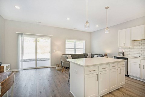 A kitchen with white cabinets and a wooden floor.