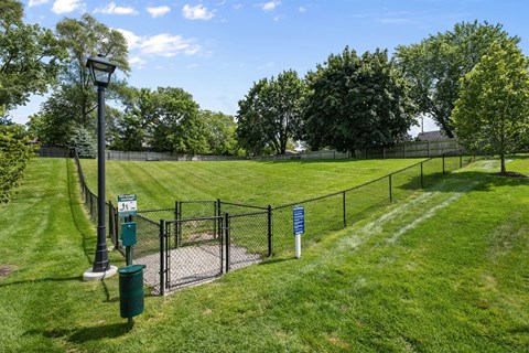 A green sign is on a pole in a grassy area.