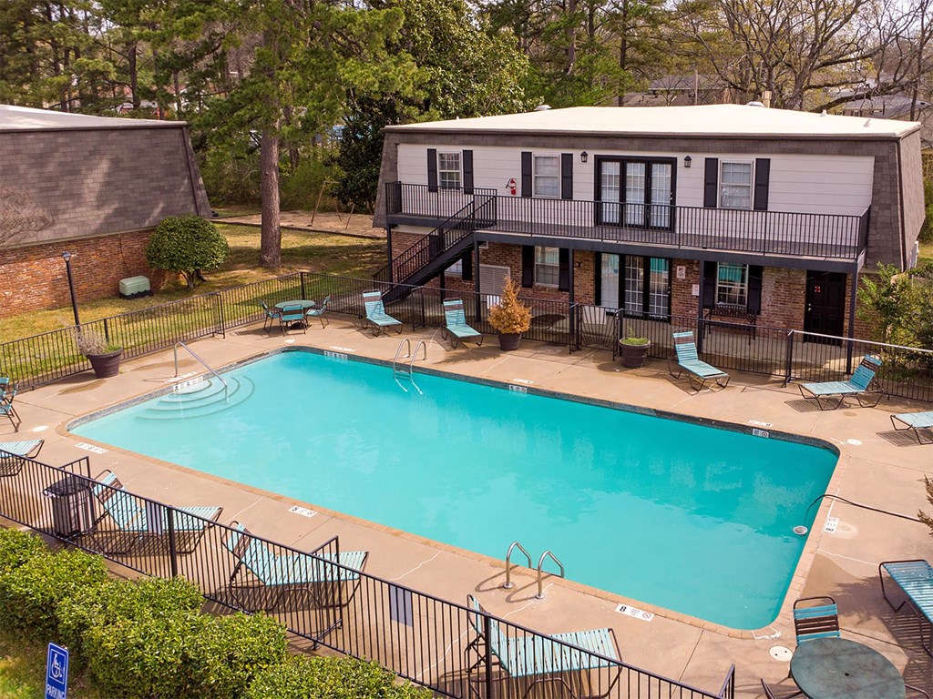 A small pool surrounded by a black fence and chairs.