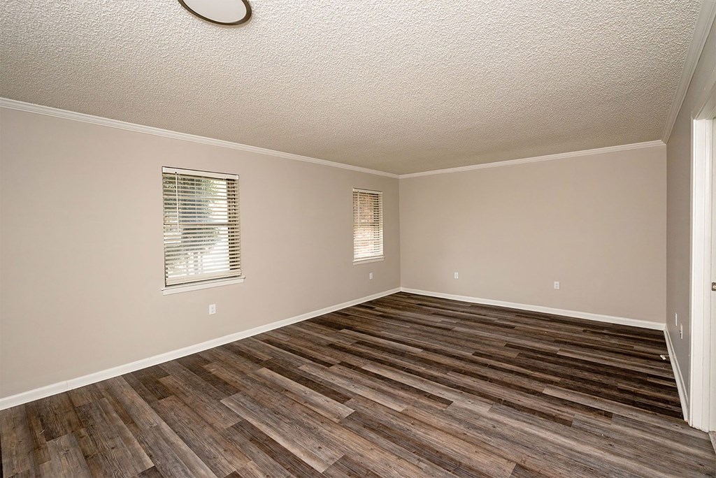 A room with wooden flooring and a window with blinds.