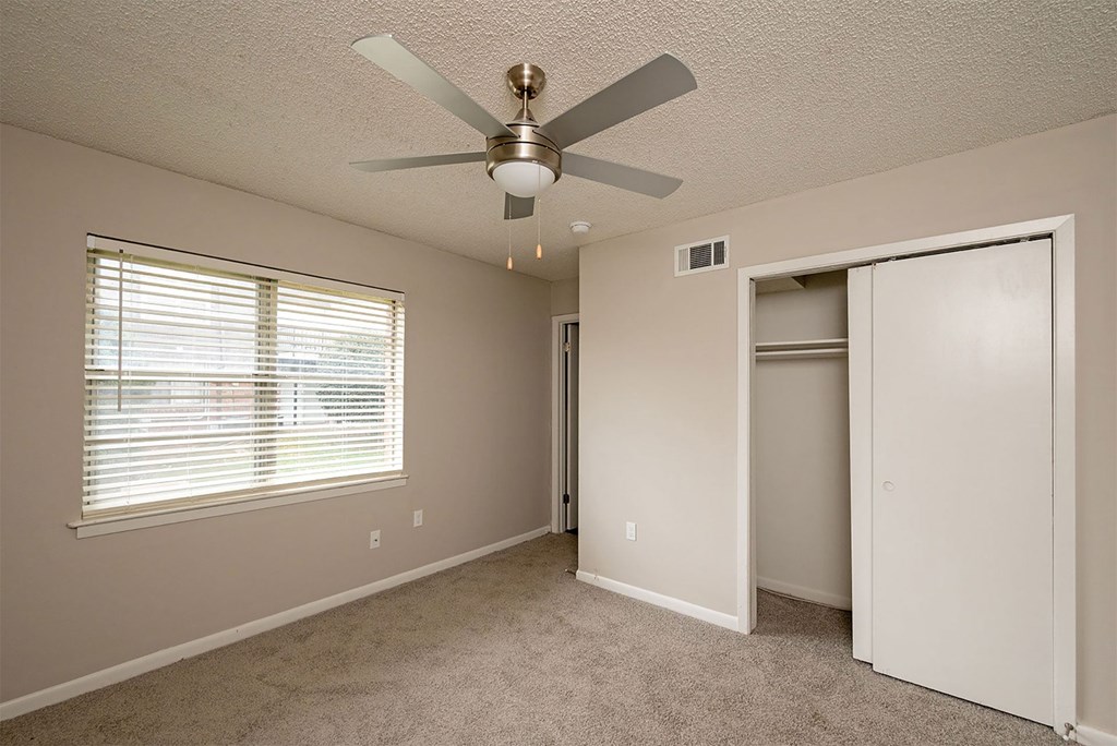 A room with a ceiling fan and a window with blinds.