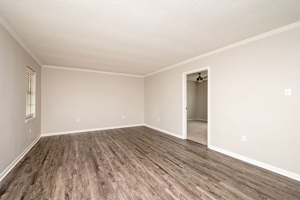 A room with a wooden floor and a doorway leading to another room.