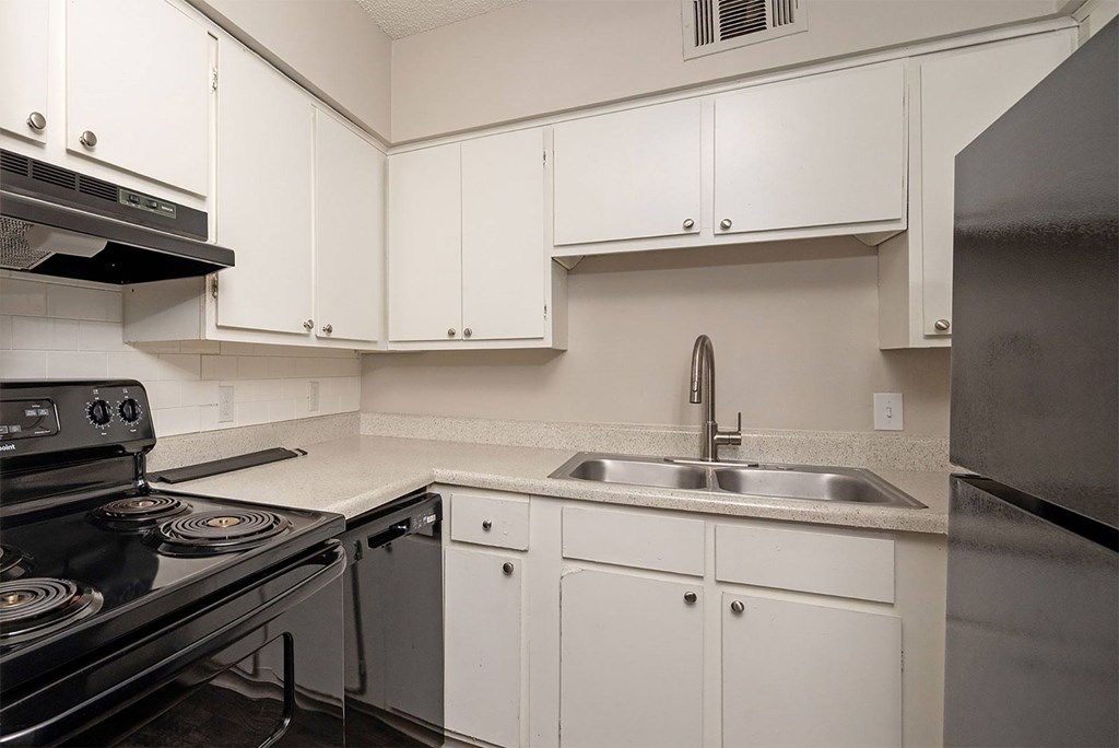 A kitchen with white cabinets and a black stove top.