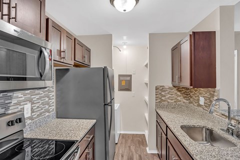 A kitchen with a stove top oven, microwave, refrigerator, and sink.