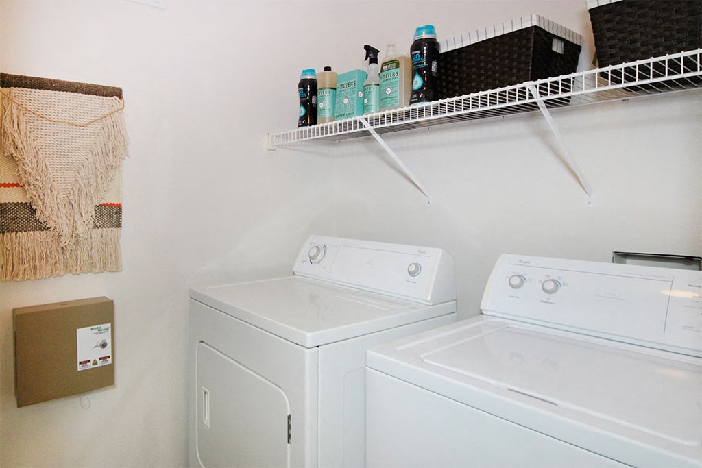 a white washer and dryer in a laundry room with a shelf above it