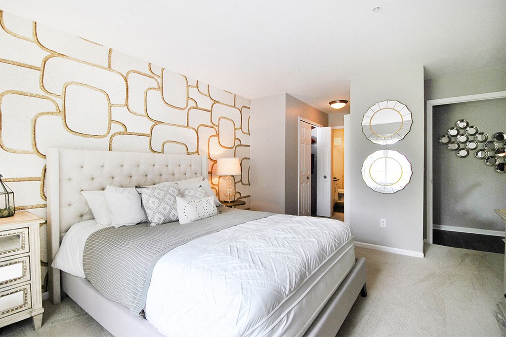 a bedroom with a large bed and a wall with a mirror