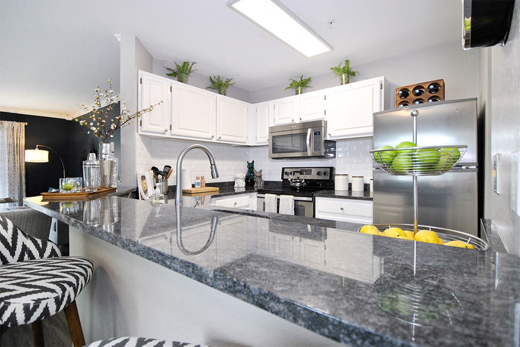 a kitchen with a marble counter top and a stainless steel refrigerator