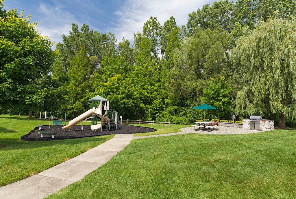 a playground with a slide and picnic table in a park